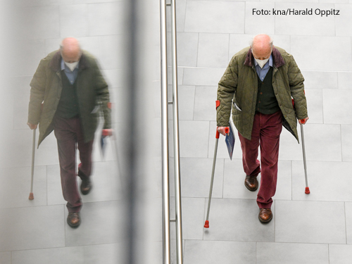 Ein alter Mann geht an Krücken einen Gang entlang zu den Impfpunkten im Corona-Impfzentrum in Bonn am 8. Februar 2021. Seine Silhouette spiegelt sich in einer Glaswand.