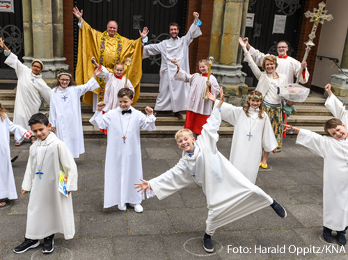 	Erstkommunionkinder in weißen Alben posieren für ein Gruppenbild nach der Messe zur Feier der Erstkommunion am 21. Juni 2020 in einer Kirche in Bonn. Auf den Boden sind Kreise gemalt, um den Abstand einzuhalten.