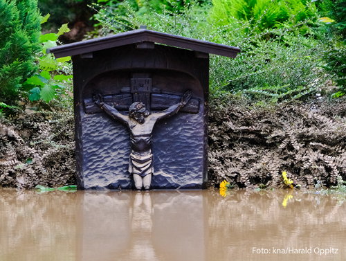 Ein Kreuz ist von braunem Wasser überschwemmt worden und nur noch zur Hälfte zu sehen 