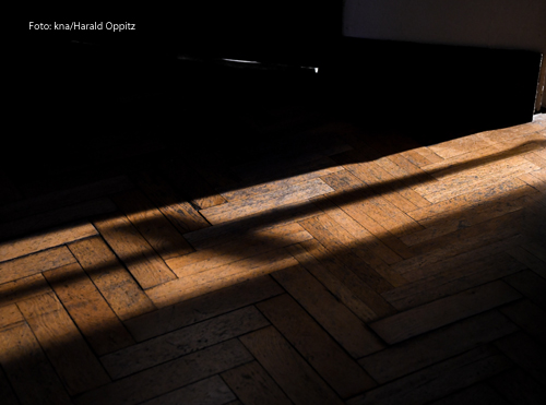 Der Schatten eines Kreuzes fällt durch eine Tür.