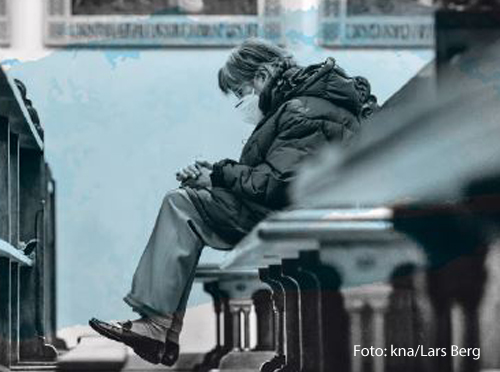 Eine Frau sitzt in einer Kirchenbank. 