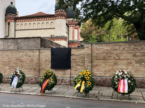 Blumenkränze lehnen an der Mauer der Synagoge in Halle
