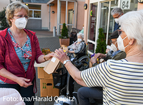Eine Frau verteilt Päckchen vor einem Pflegeheim.