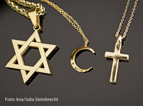 Ein goldener Davidstern, ein Halbmond und ein Kreuz liegen nebeneinander.