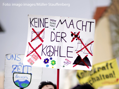 Ein Demonstrant hält bei einer Klimademonstration ein Plakat hoch. "Keine Macht der Kohle" steht darauf. 