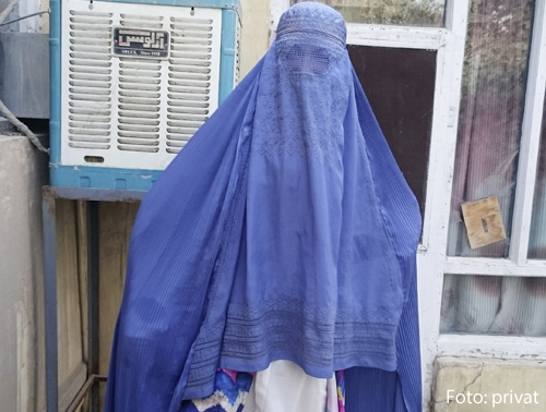 Eine junge Frau ist unter einem blauen Schleier verhüllt.