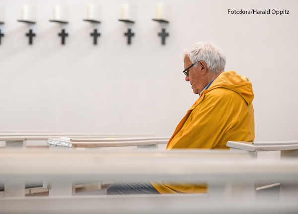 Ein Mann sitzt allein in einer Kirchenbank.