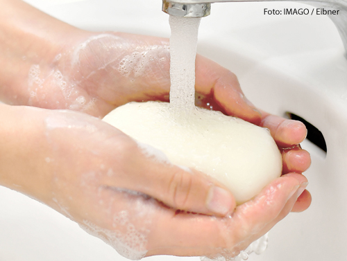 Eine Frau wäscht sich die Hände mit Seife. 