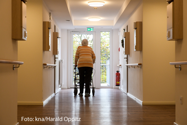 Eine Seniorin läuft in einem Altenheim über einen Flur. 