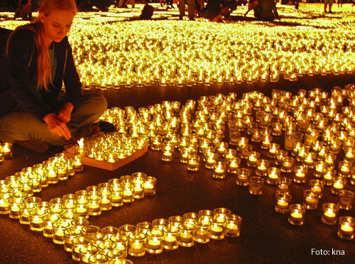 Ein Mädchen sitzt in mitten hunderter brennender Kerzen. 