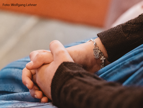 Eine Frau hat ihre Hände zum Gebet gefaltet.  