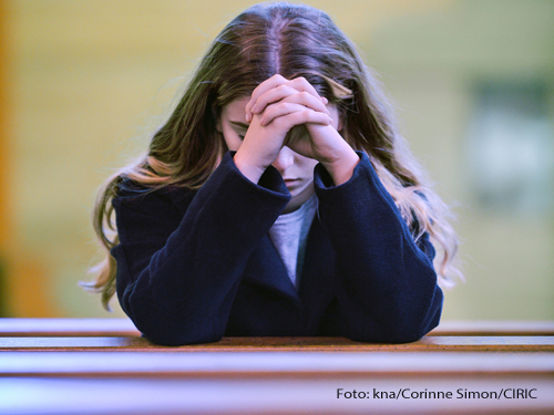Eine Frau betet in der Kirche. Foto: kna/Corinne Simon/CIRIC