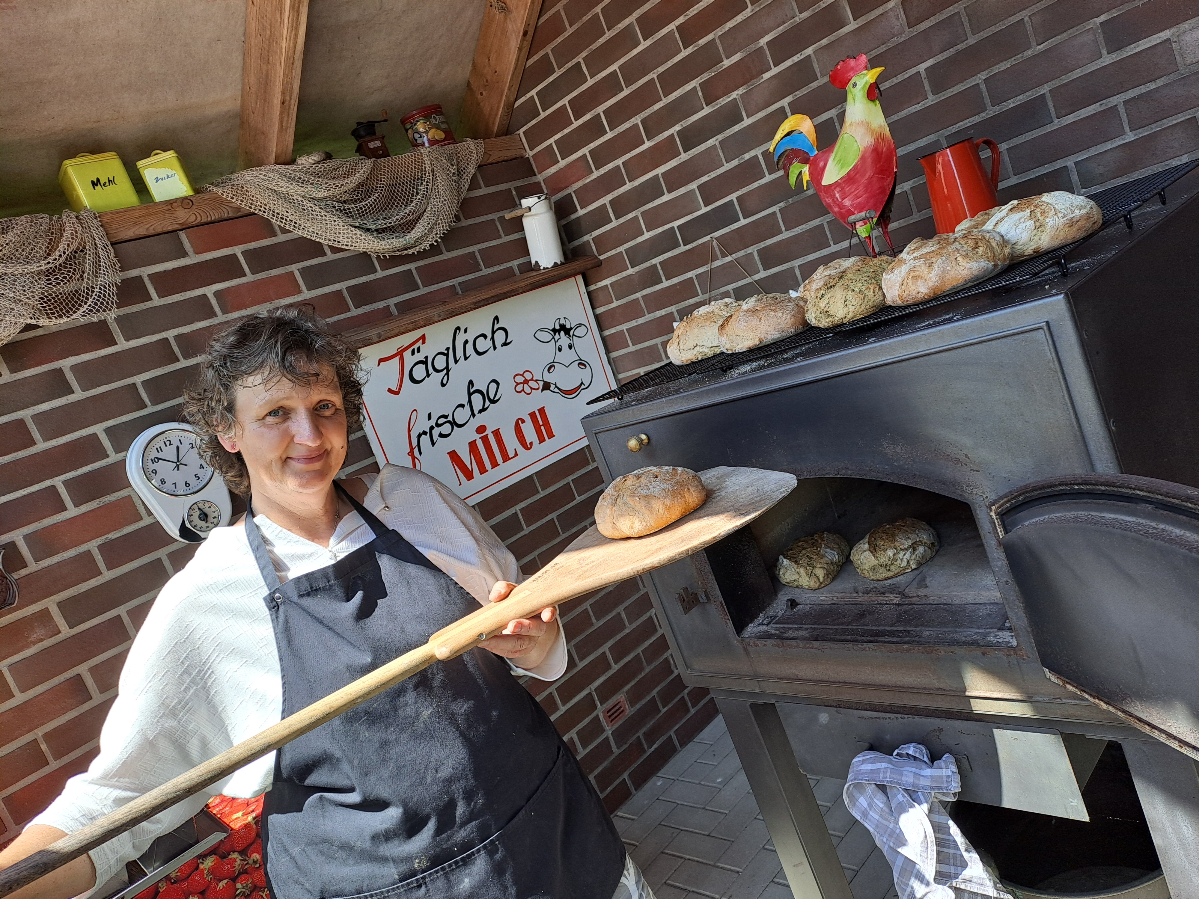 Eine Frau holt Brot aus dem Ofen
