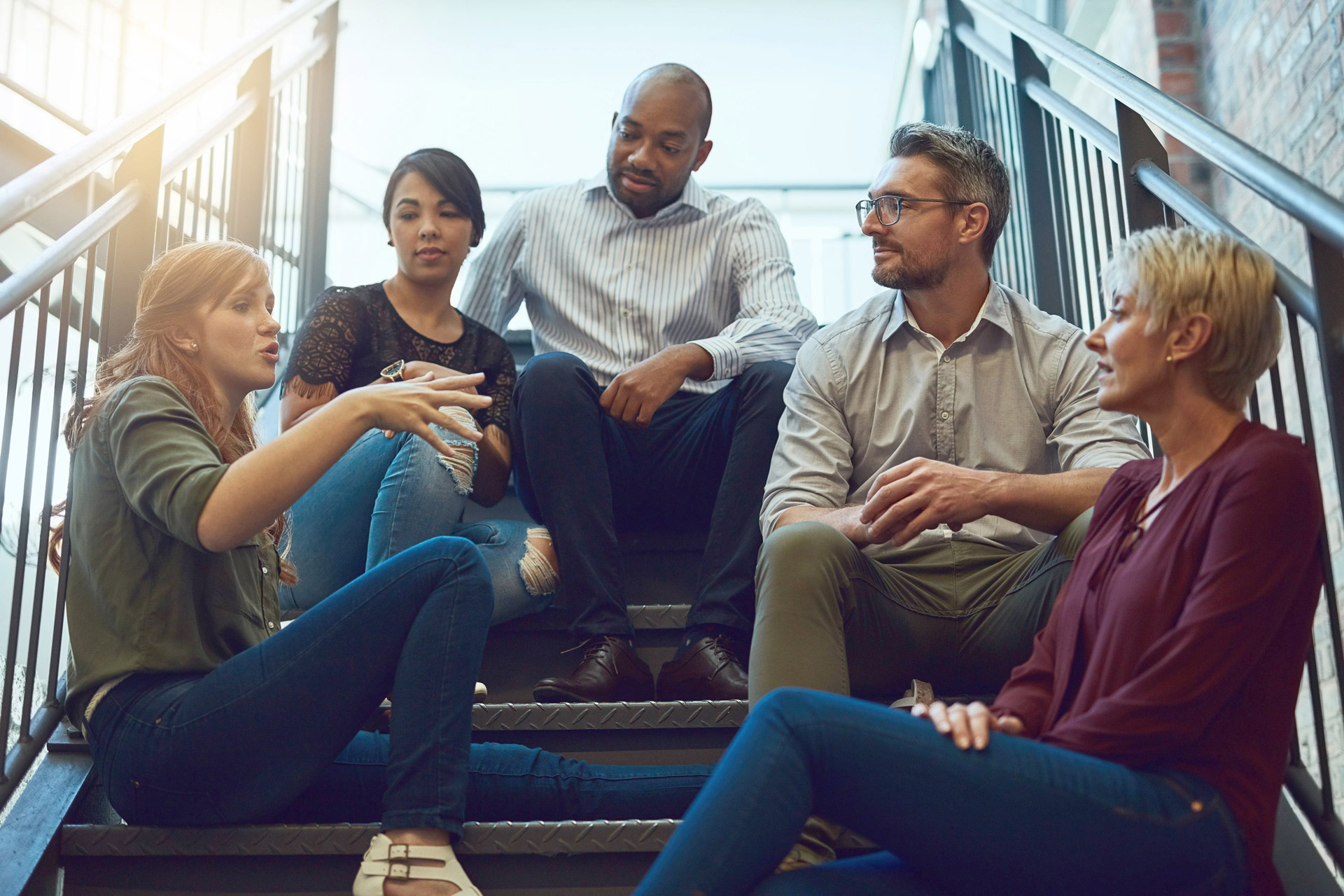 fünf Menschen sitzen auf einer Treppe und quatschen