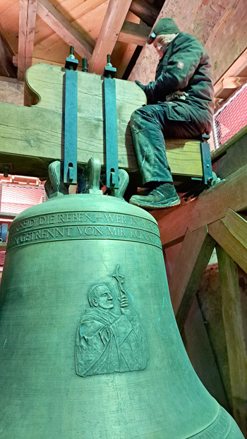 Mechaniker sitzt auf einer Kirchenglocke