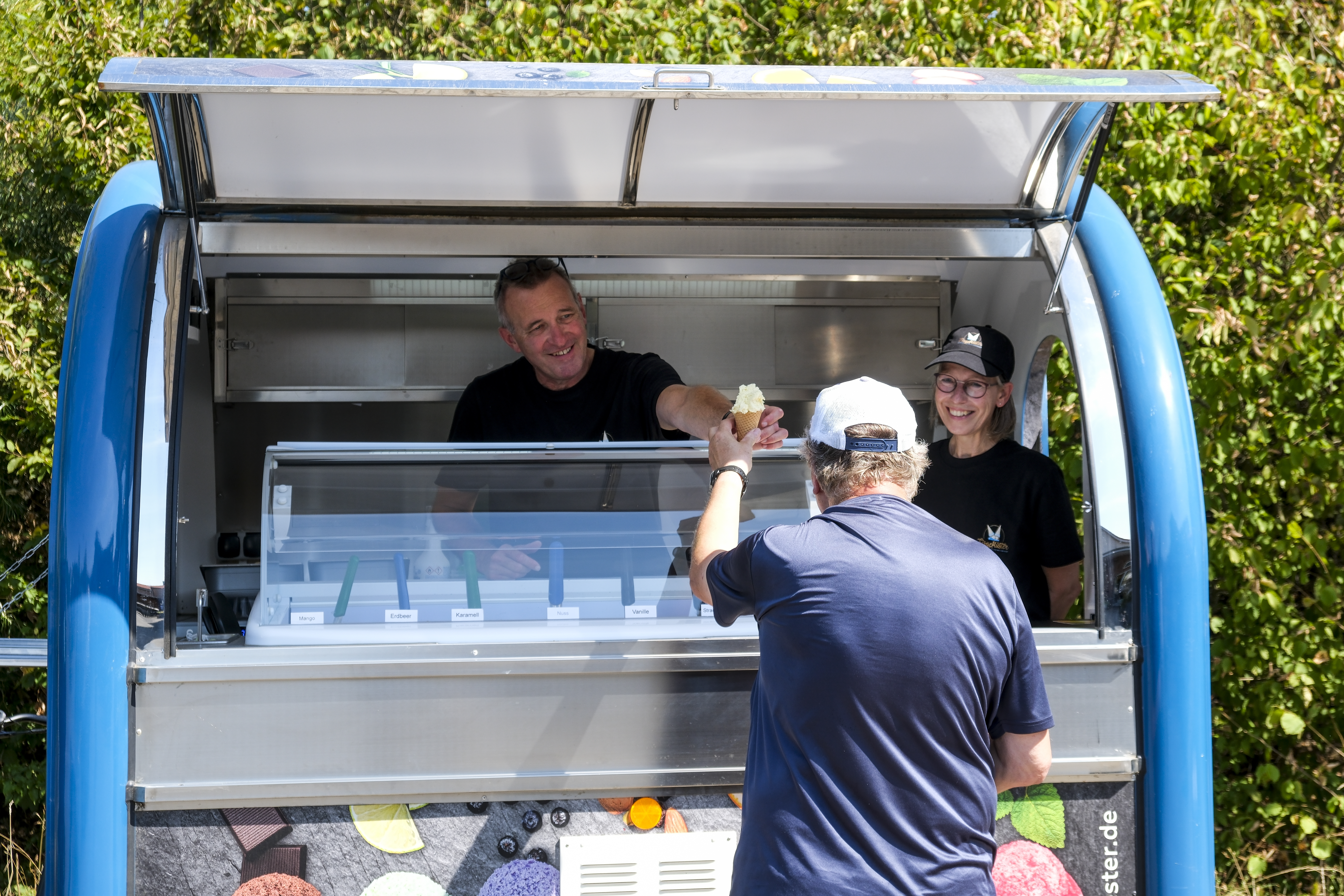 Zwei Menschen im Eiswagen geben ein Eis raus