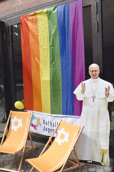Papp-Aufsteller von Papst Leo XIV. neben einer Regenbogenflagge