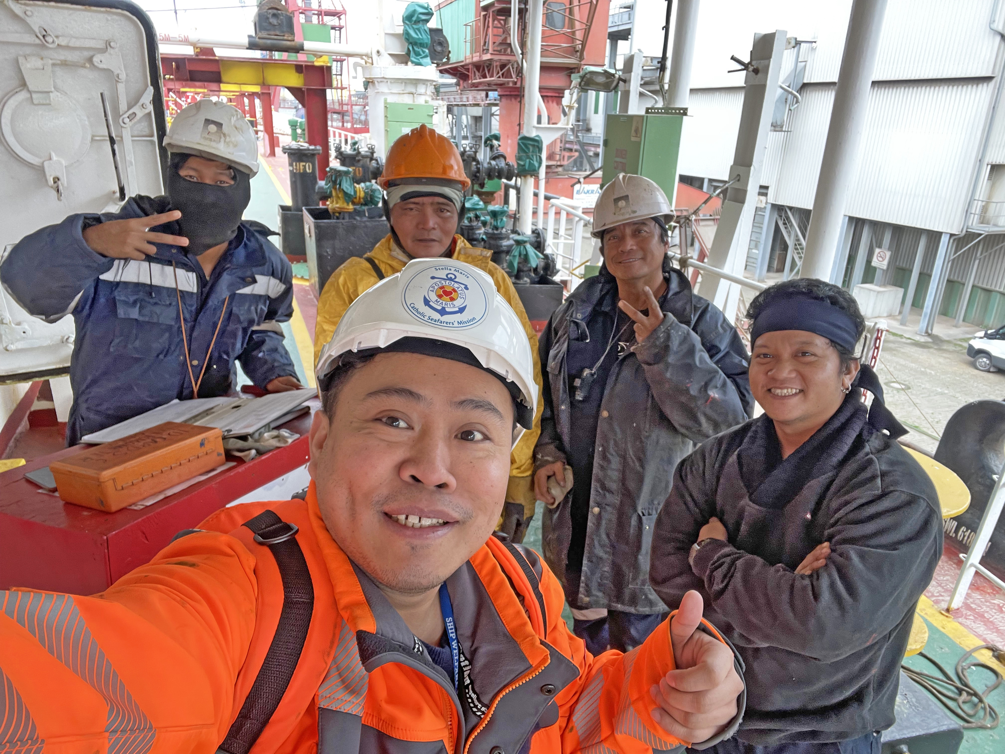 Fünf Seeleute auf dem Schiff lächeln in die Kamera