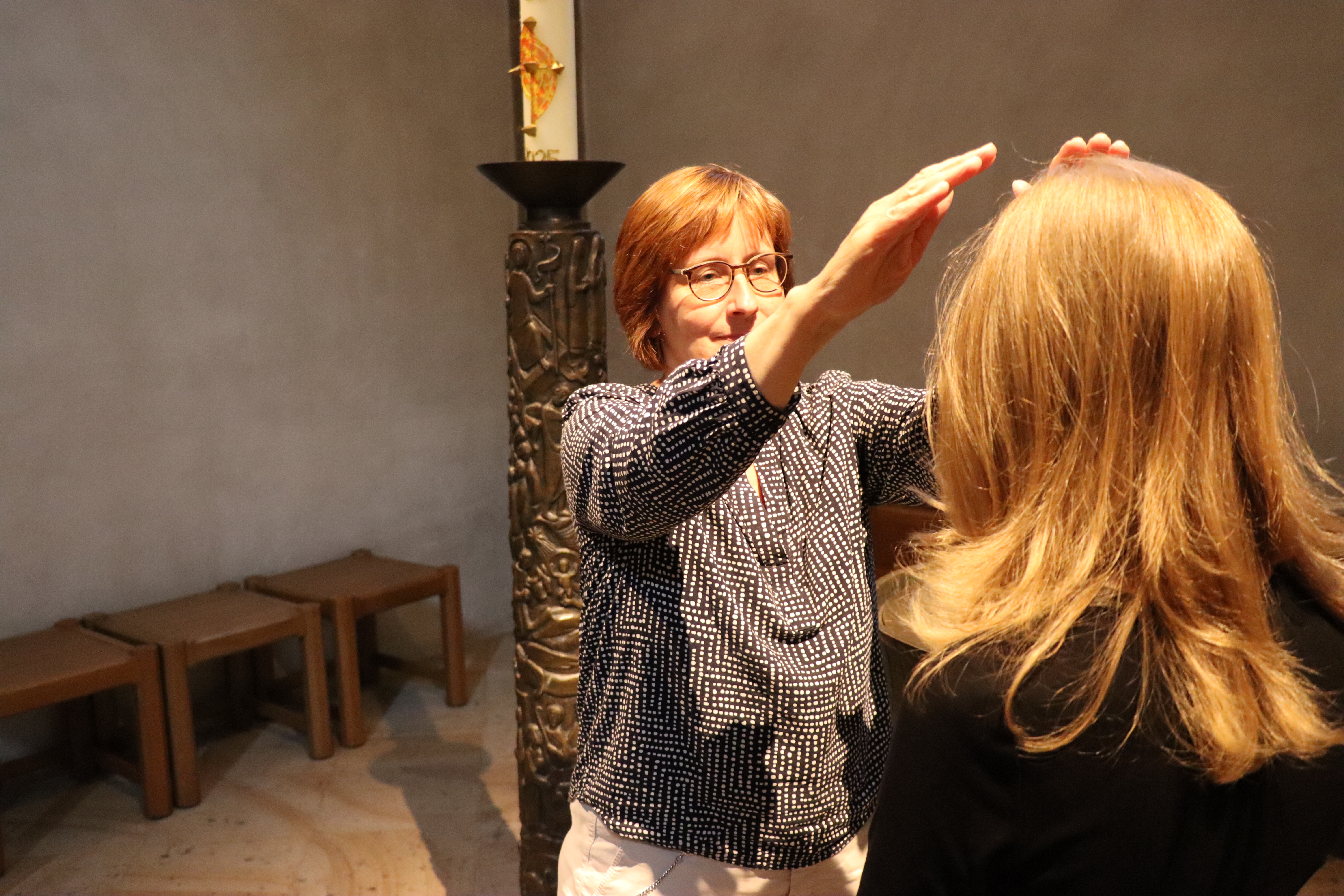 Eine Frau legt einer anderen Frau die Hände segnend auf den Kopf