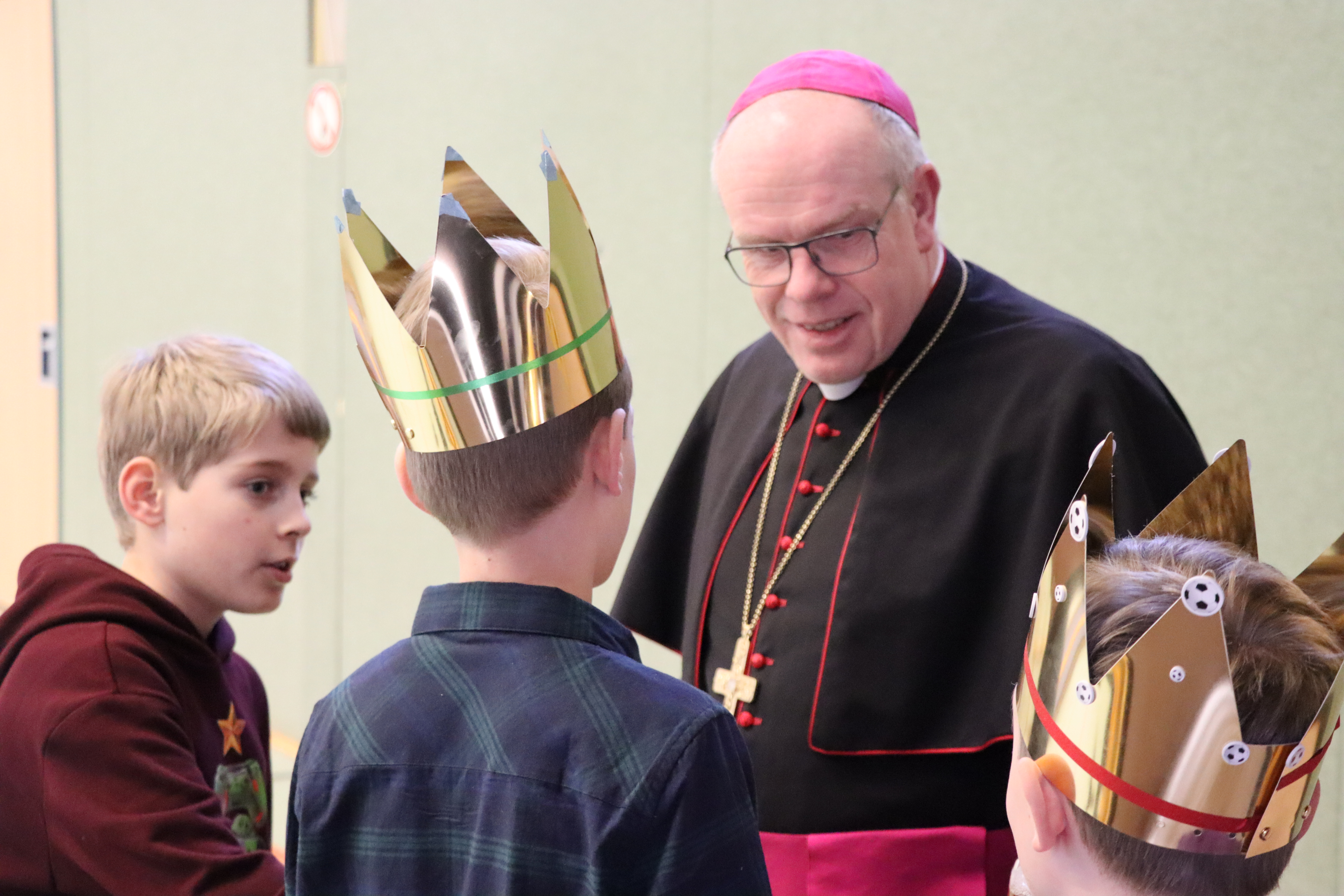 Weihbischof Wübbe im Gespräch mit drei Jungen