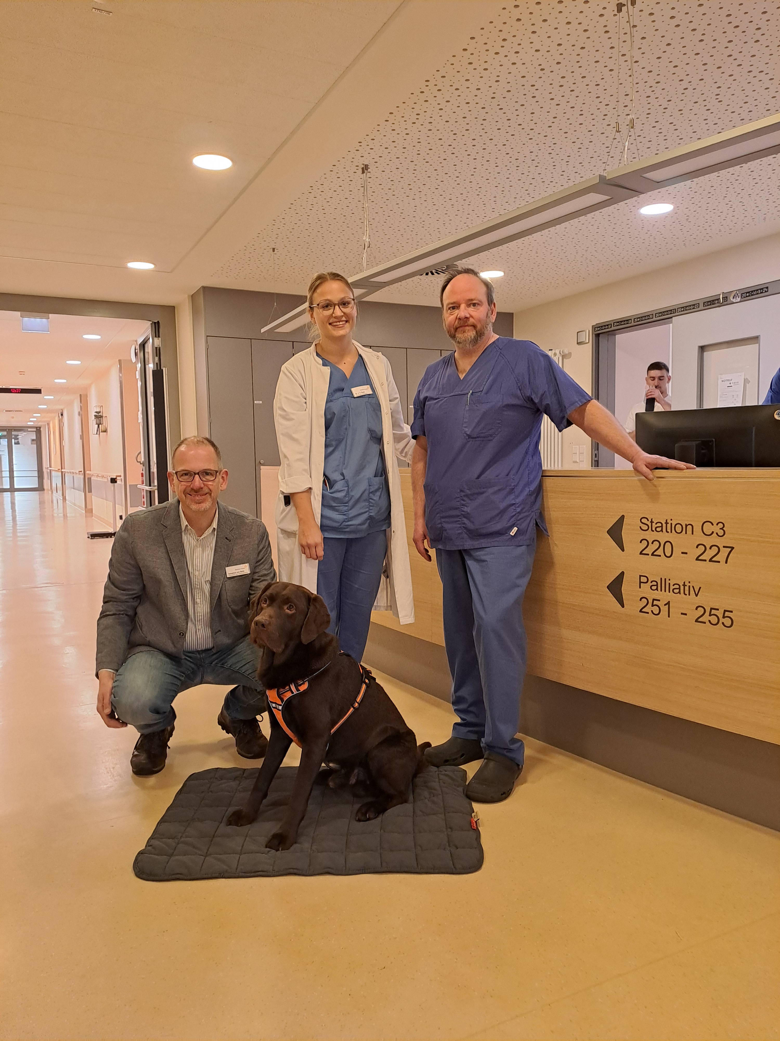 Drei Menschen mit einem Hund im Krankenhaus