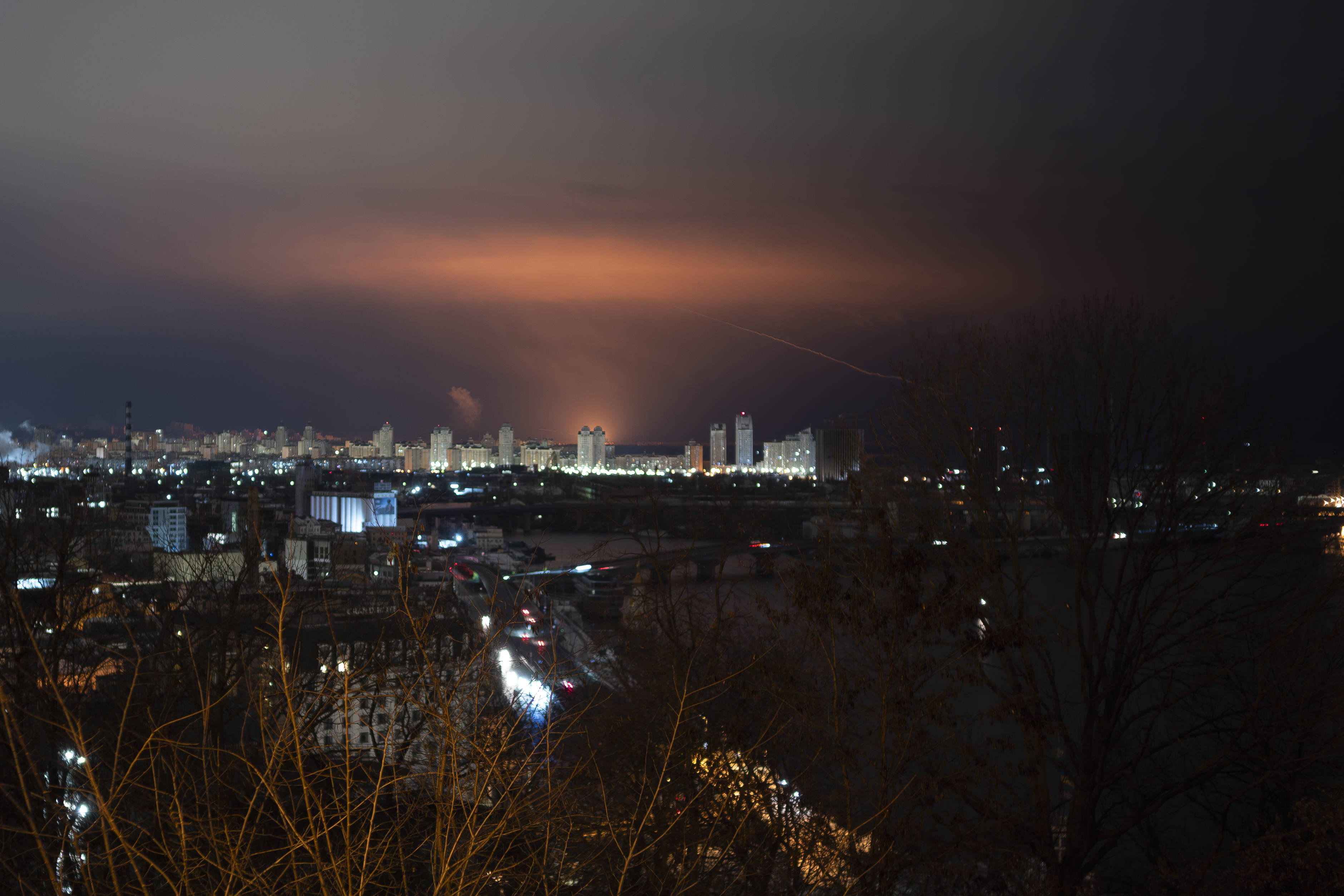 Kiew bei Nacht. In der Ferne färben Drohnenangriffe den Himmel rot. 