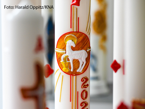 Eine Osterkerze ist mit einem Lamm verziert und steht auf einem Tisch eines Kerzenherstellers in Köln. 