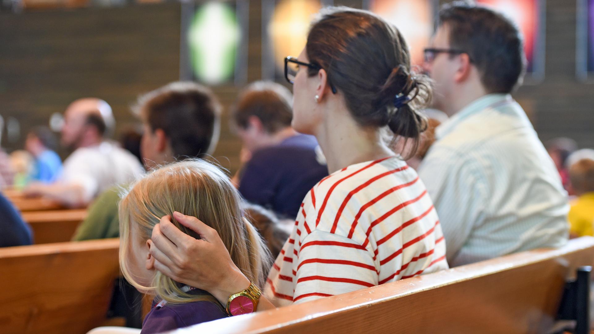 Eltern und Geschwisterkind sitzen in einer Kirchenbank