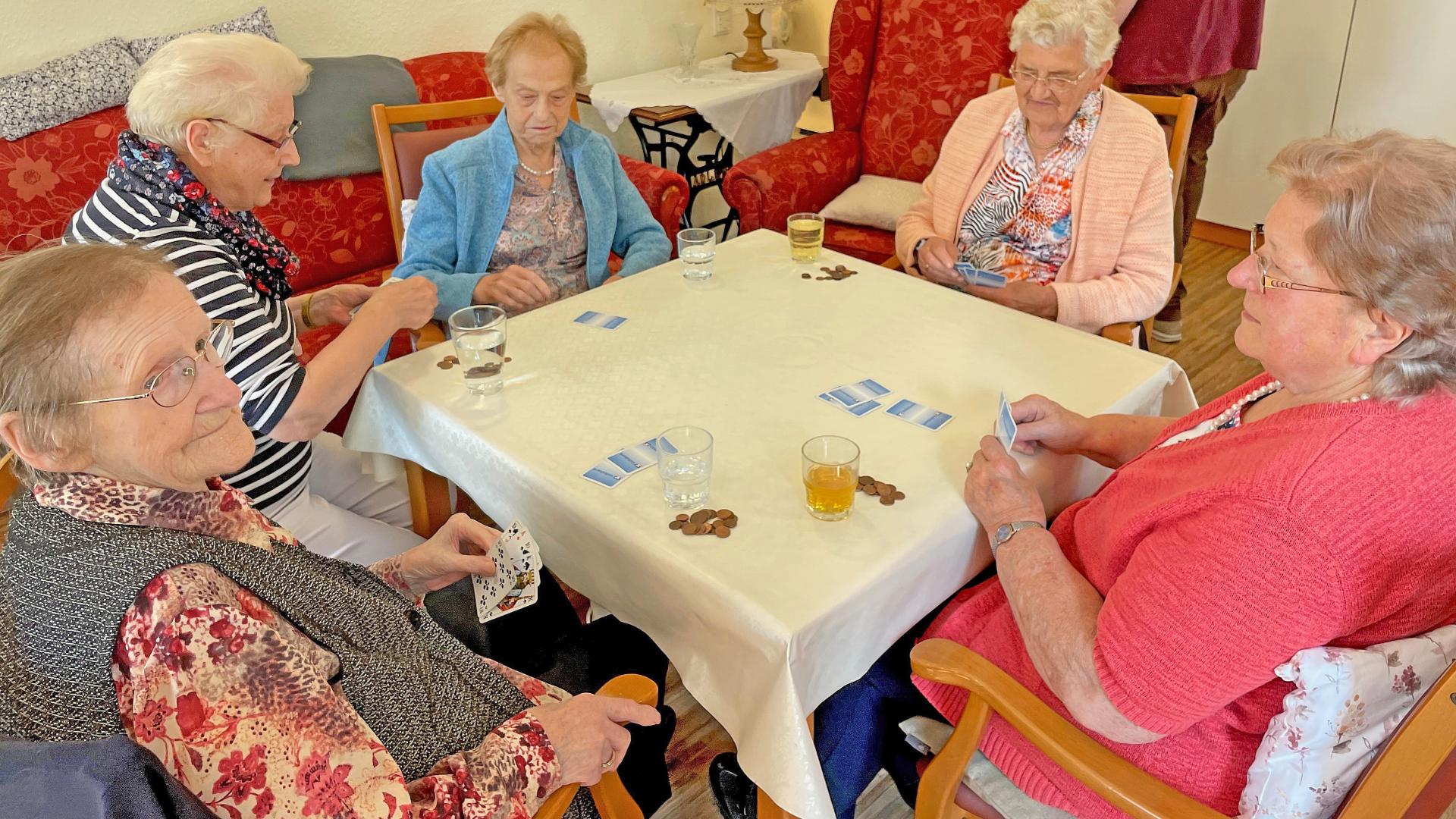 ältere Frauen sitzen an einem Tisch und spielen Karten