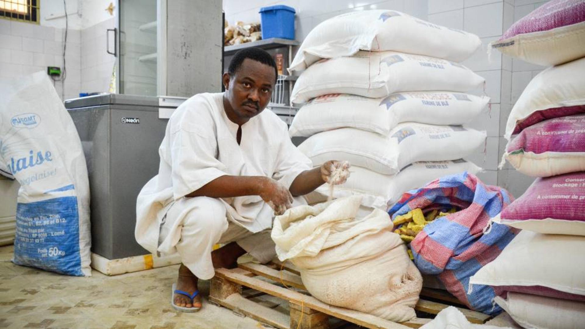Bäcker Daniel Agblevon sitzt vor Säcken mit Weizenmehl im Lagerraum seiner Backstube in Lome (Togo) im Jahr 2021.