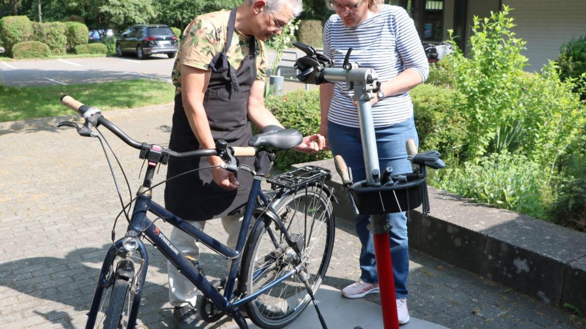 Mann repariert Fahrrad, Frau steht daneben