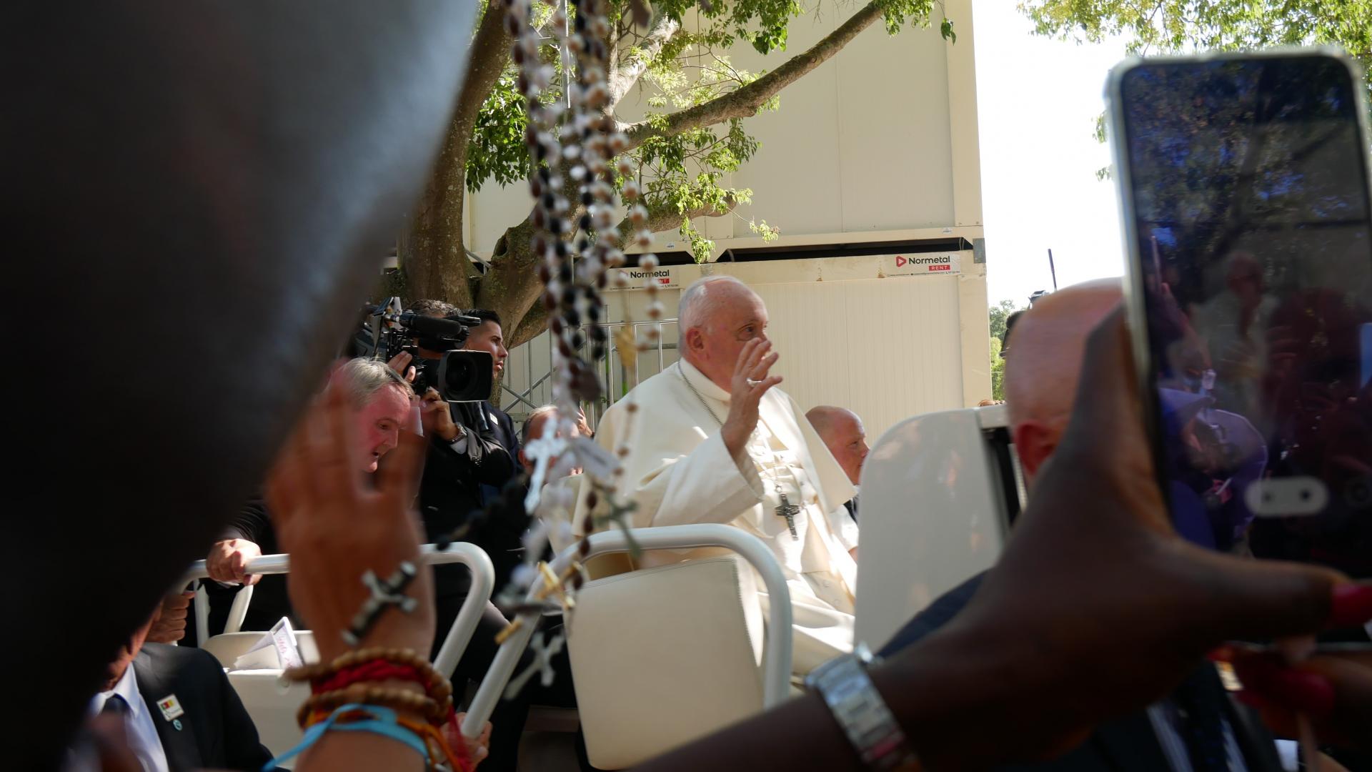 Papst Franziskus fährt vorbei, während er mit Handys gefilmt wird.