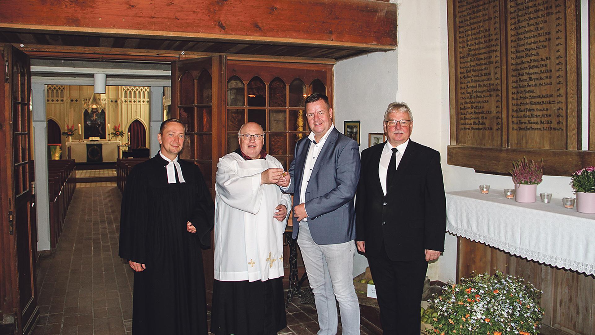 Pastoralreferent Herbert Wolf überreicht Amtsleiter Marko Kinski ein Fläschchen mit Gold. Pastor Christian Hasenpusch und  Michael Herm, Priester der Neuapostolischen Kirche.