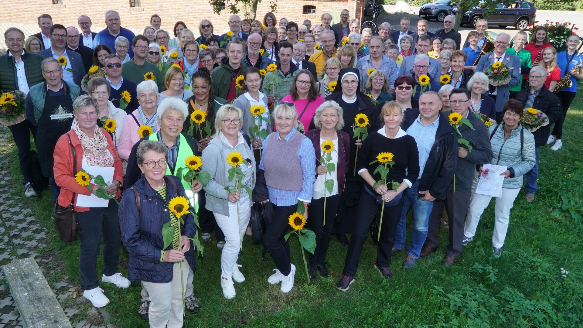 Eine große Gruppe Menschen, die Sonnenblumen in der Hand halten