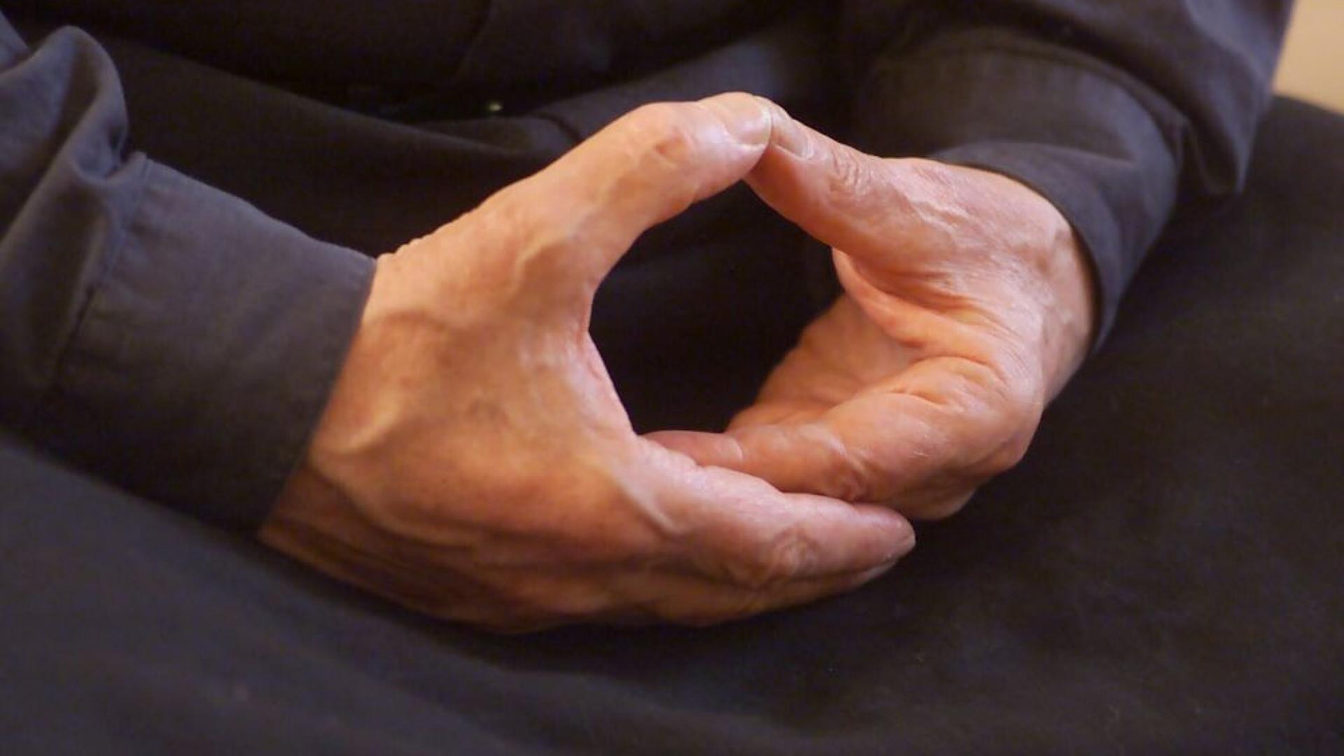 Ein Mann hält die Hände in der Meditationshaltung im Schoß
