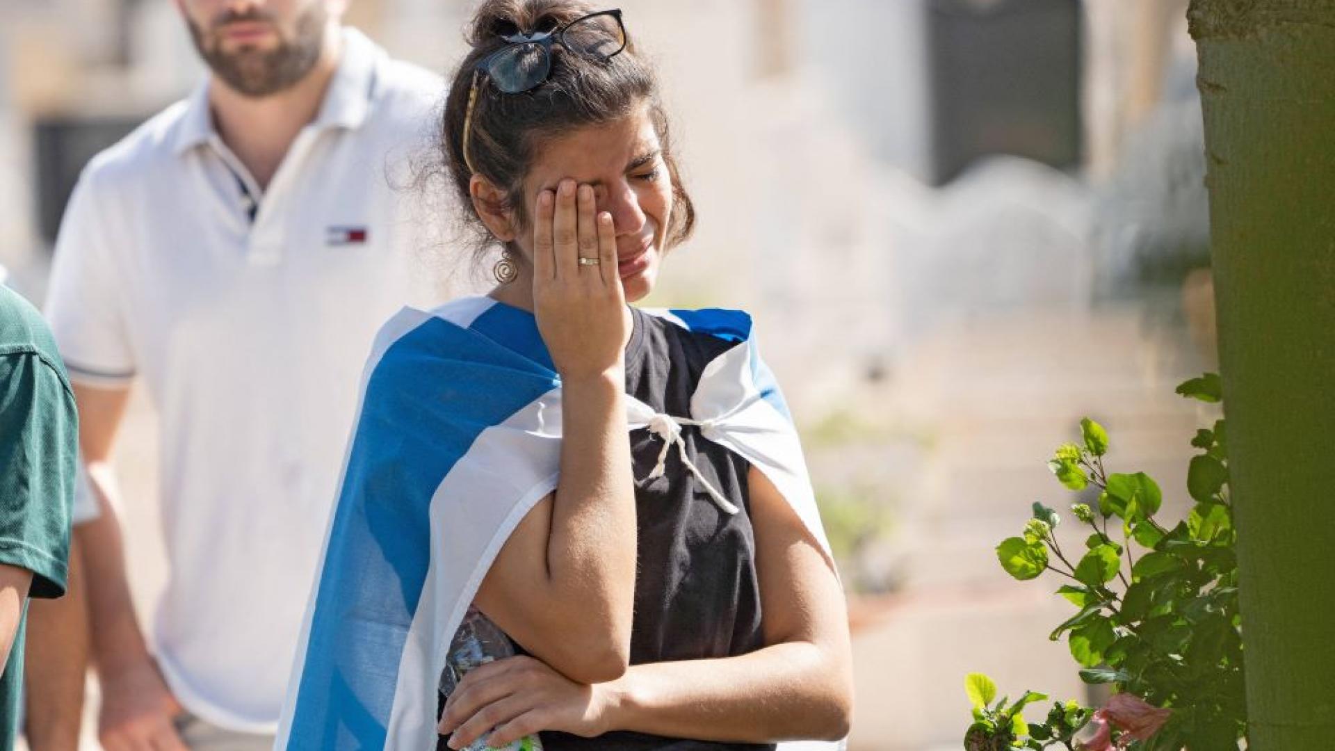 Eine Frau mit Israelfahne als Umhang weint