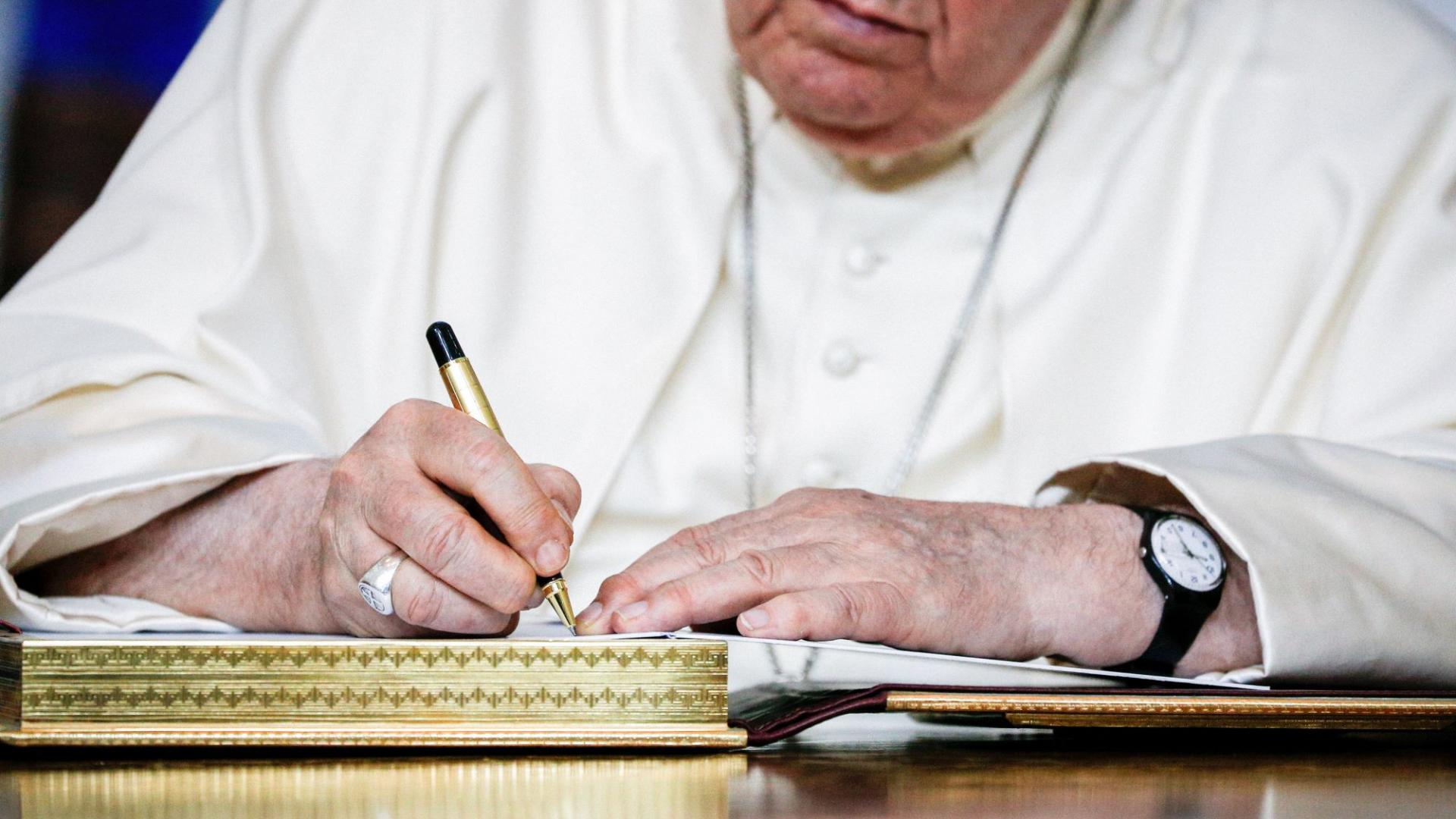 Papst Franziskus setzt seine Unterschrift in ein Buch