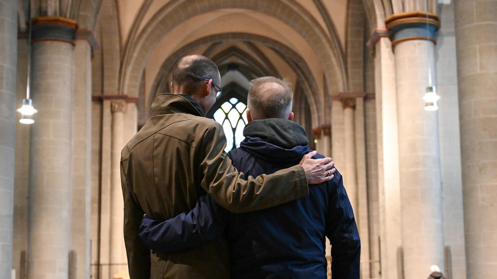 Zwei Männer umarmen sich in einer Kirche