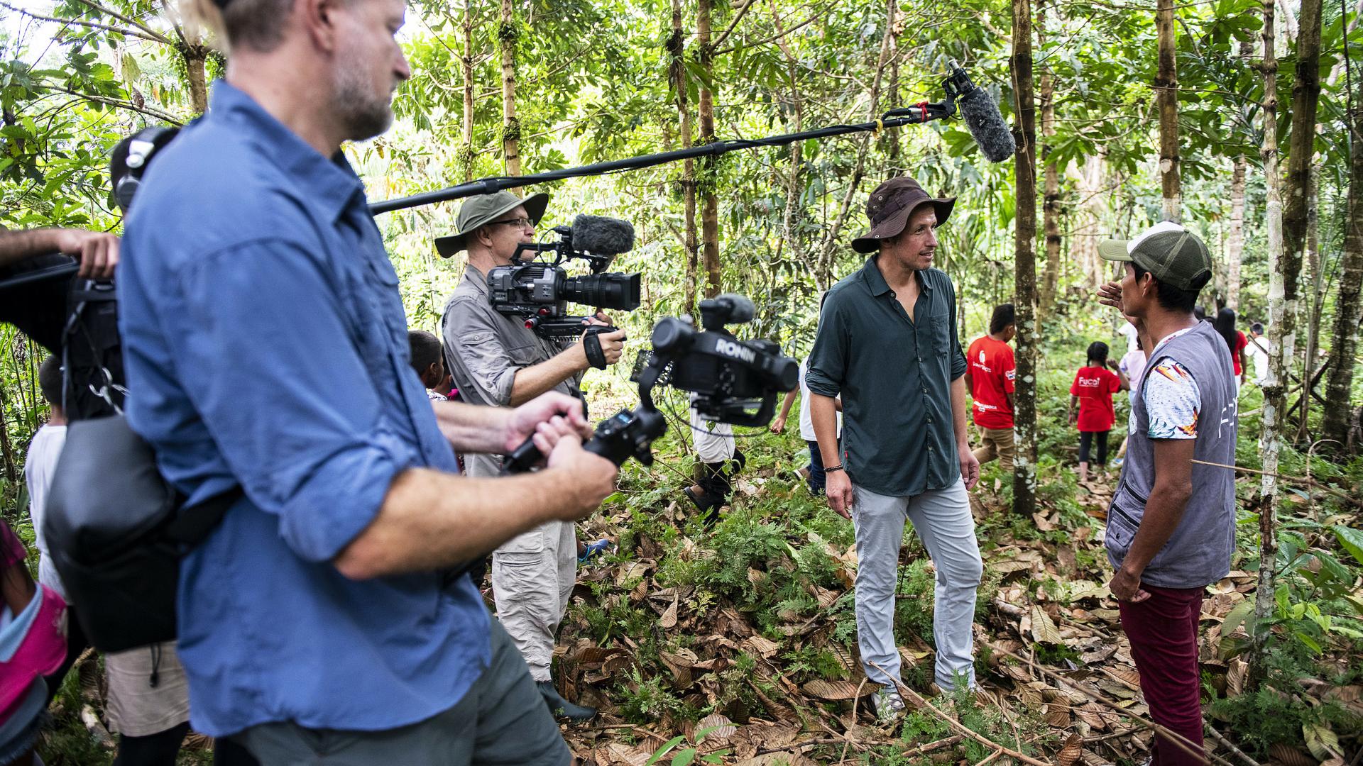 Willi Weitzel steht mit seinem Kamera-Team im Amazonas-Regenwald und führt ein Interview