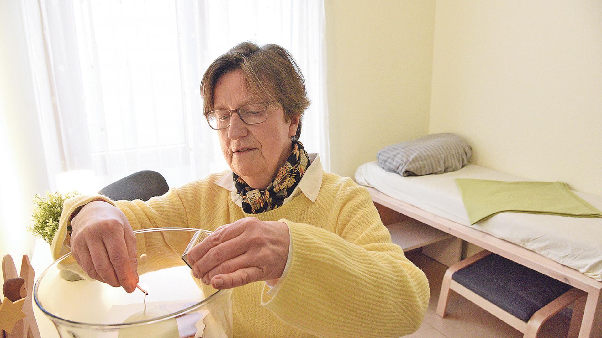 Frau zündet Kerze an