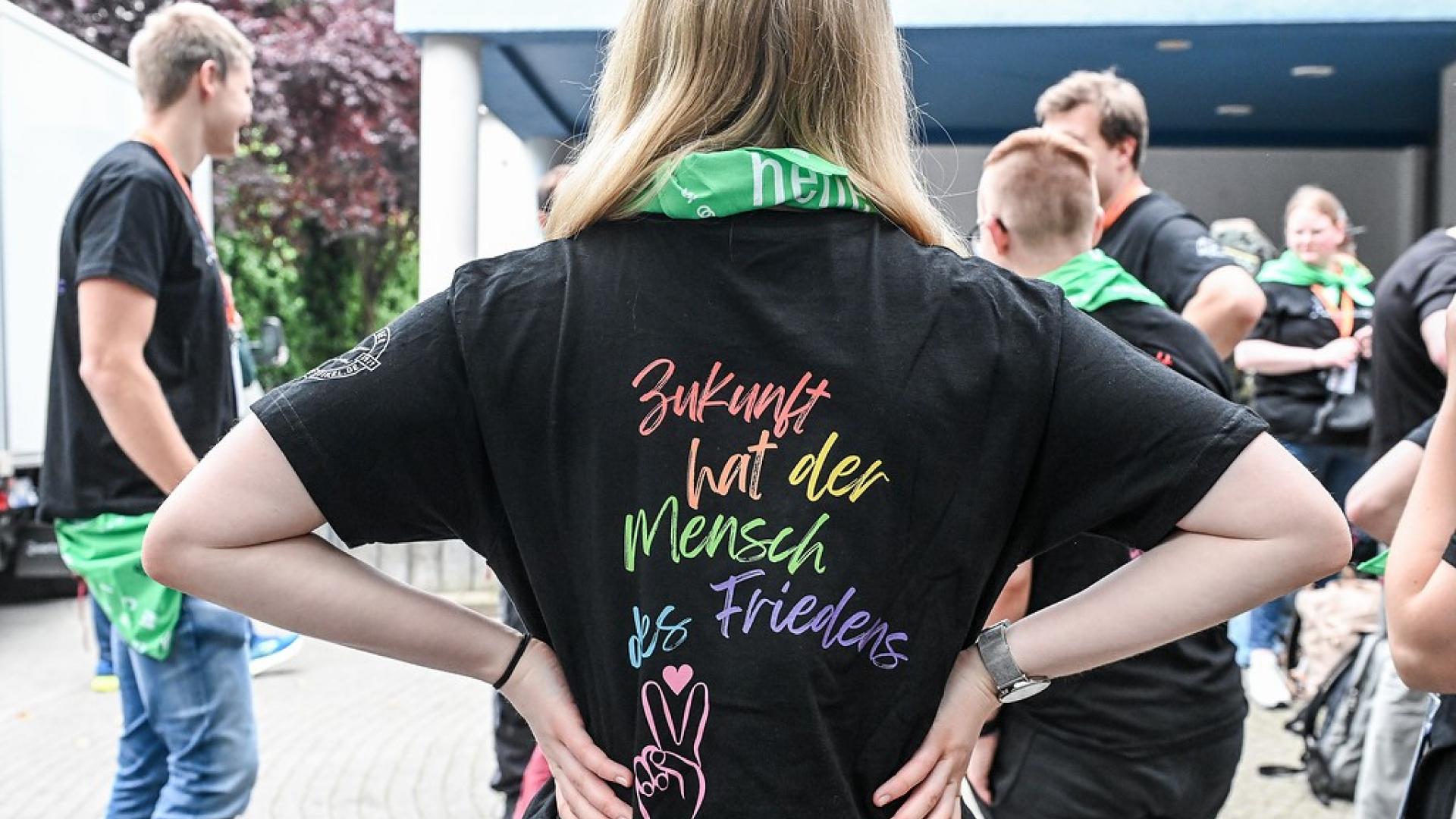 eine junge Frau trägt das Motto des Katholikentags in Erfurt auf dem Rücken ihres Shirts