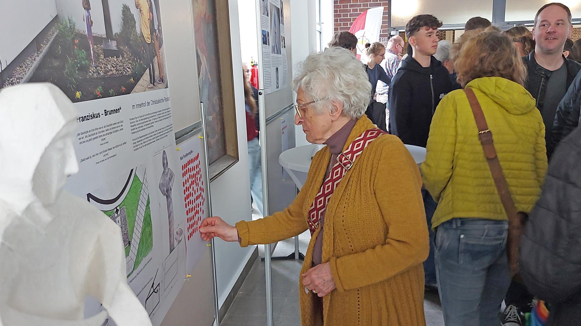 Frau klebt einen Klebepunkt auf ein Plakat.