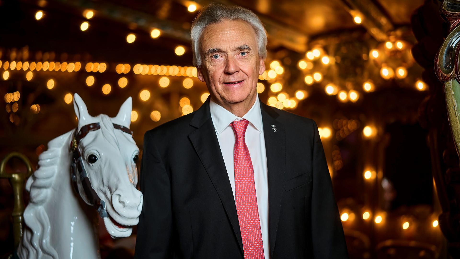 Ein Mann steht neben einem Pferd aus Plastik, im Hintergrund Lichterketten