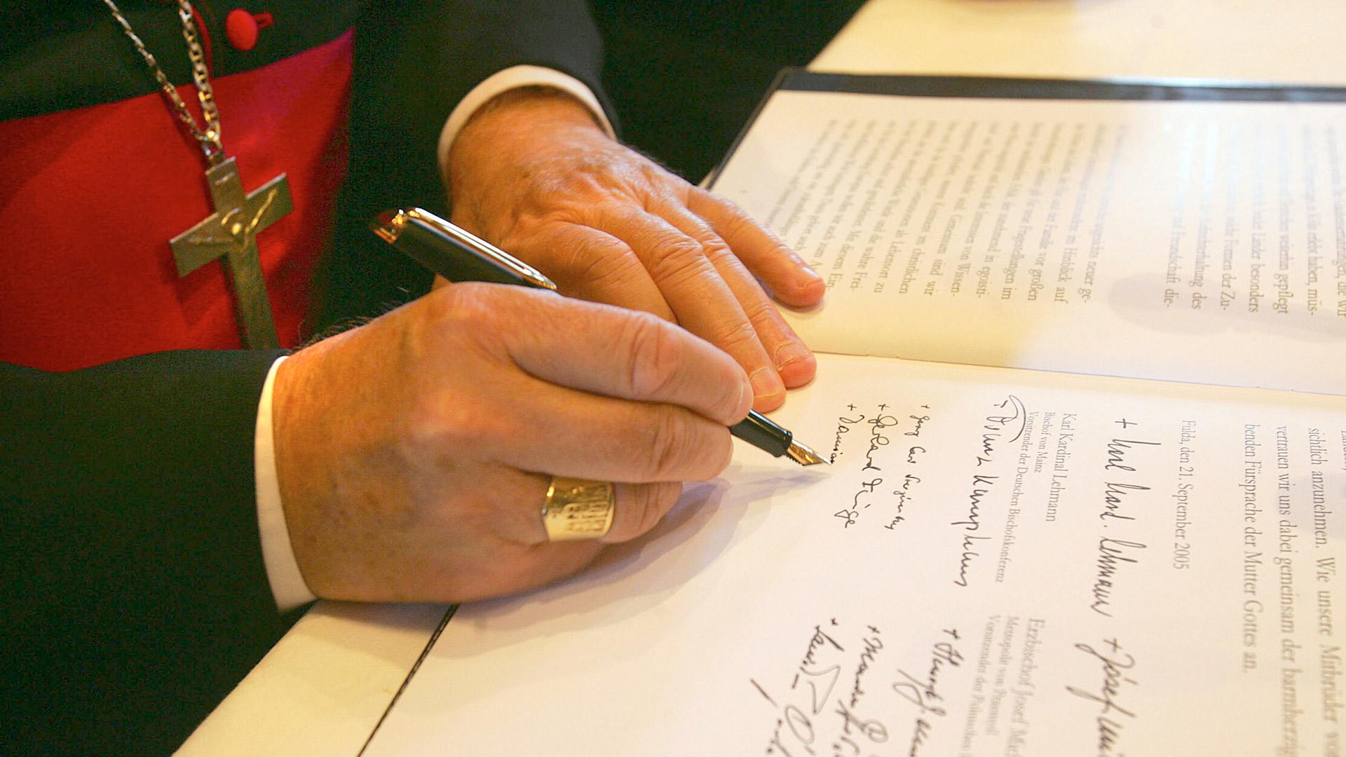 Bischofshände unterschreiben ein Dokument