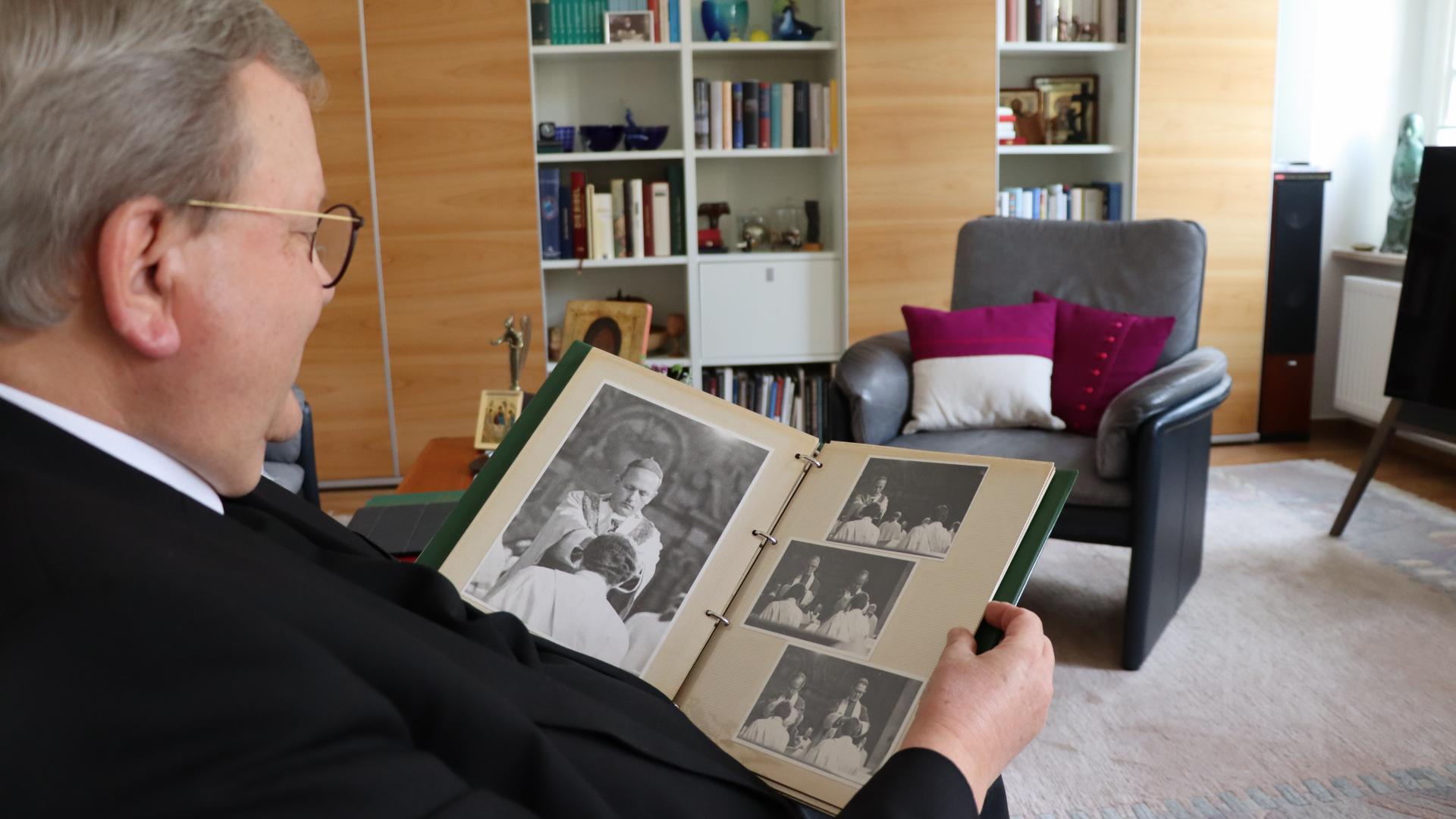 Ein Mann sitzt im Sessel und betrachtet ein Fotoalbum auf seinen Beinen