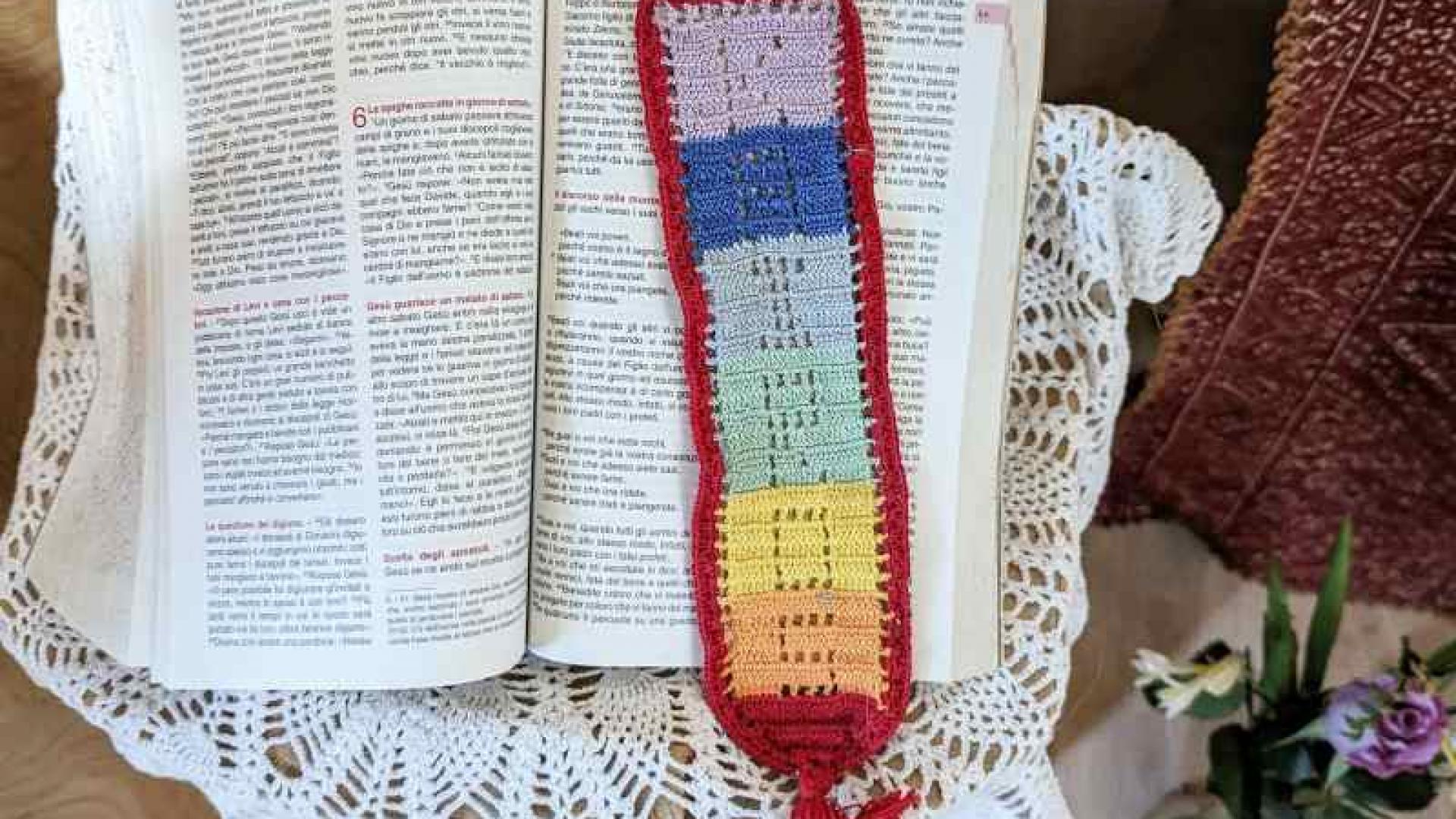 Ein buntes Lesezeichen liegt in der Bibel. Gottes Wort ist eine frohe Botschaft.