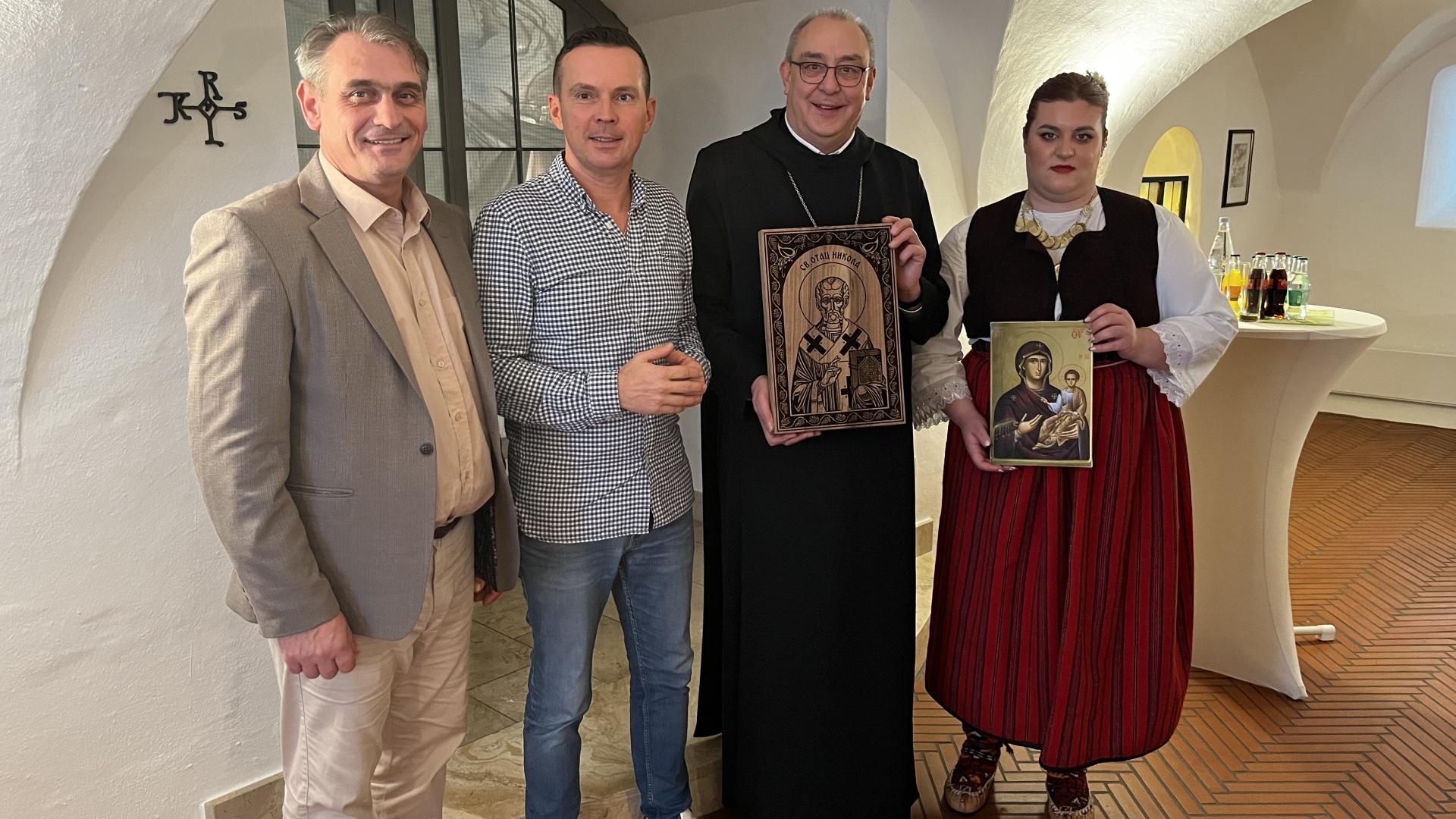 Gruppenforo mit drei Männern und einer Frau. Zwei Personen halten eine Ikone