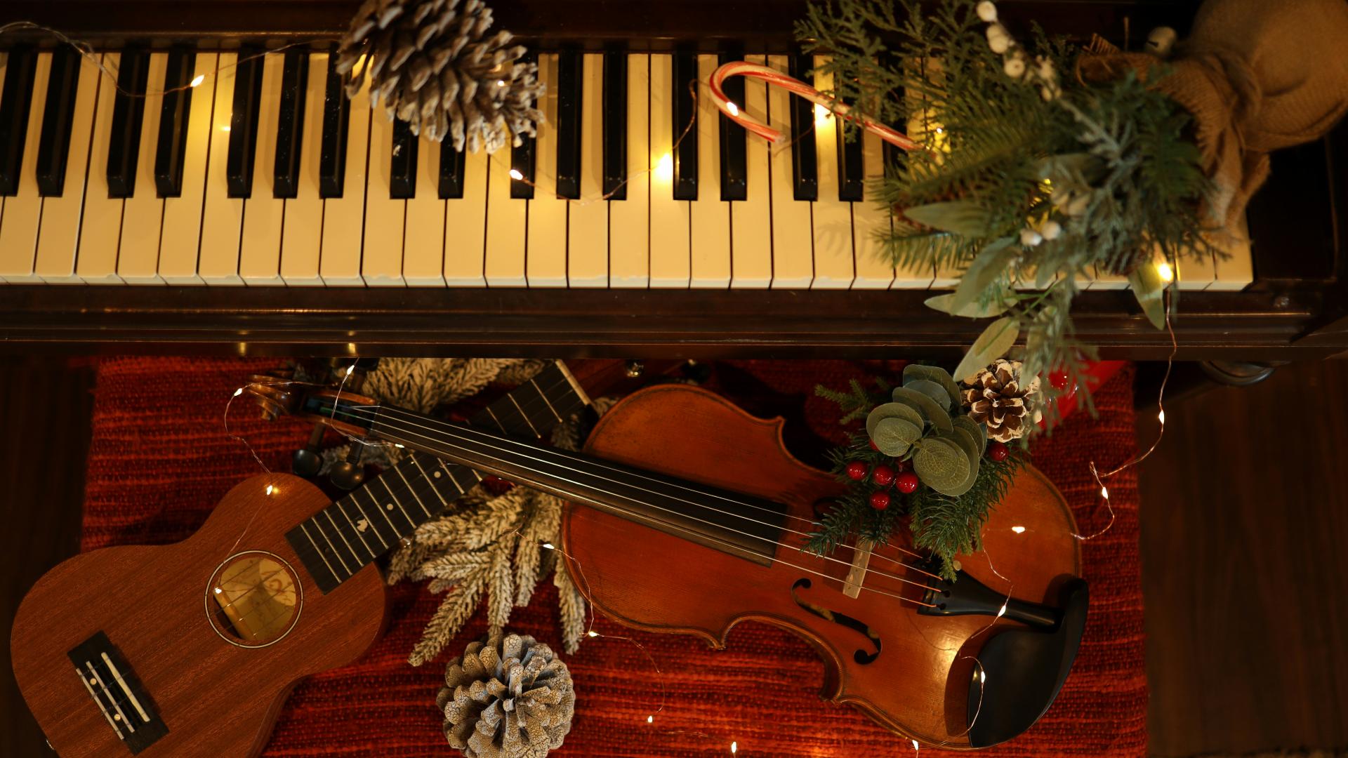Ein Klavier, weihnachtlich. Davor liegt eine Geige und eine Gitarre. 