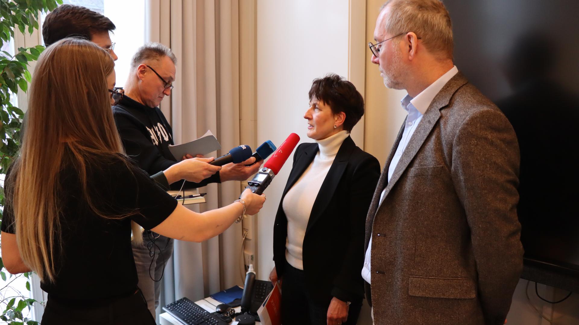 Drei Journalisten mit Mikrofonen befragen zwei Mitarbeiter des Bistums