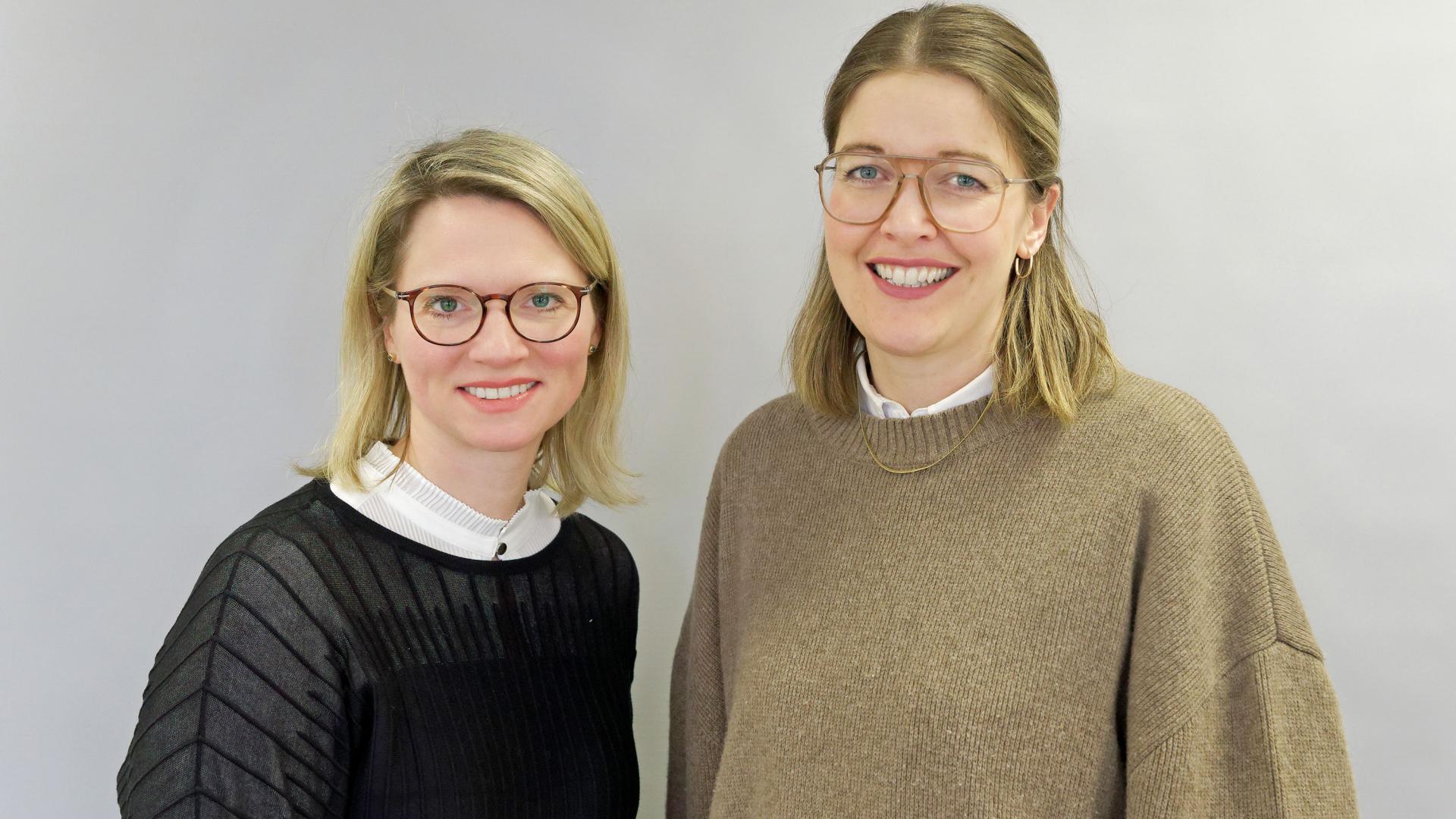 Zwei Frauen lächeln in die Kamera.